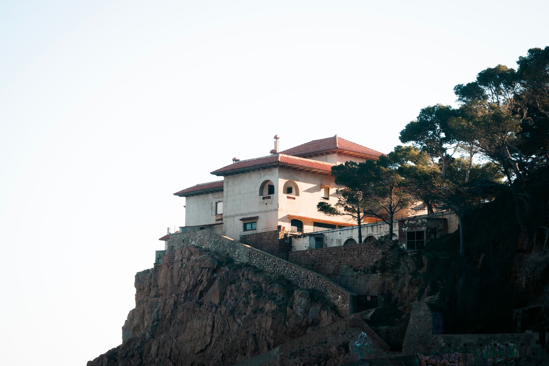 Elegant villa perched on a cliff in Costa Brava, framed by trees against a clear sky. — photograph by ✰ Saul Bandera Brotheridge on Pexels