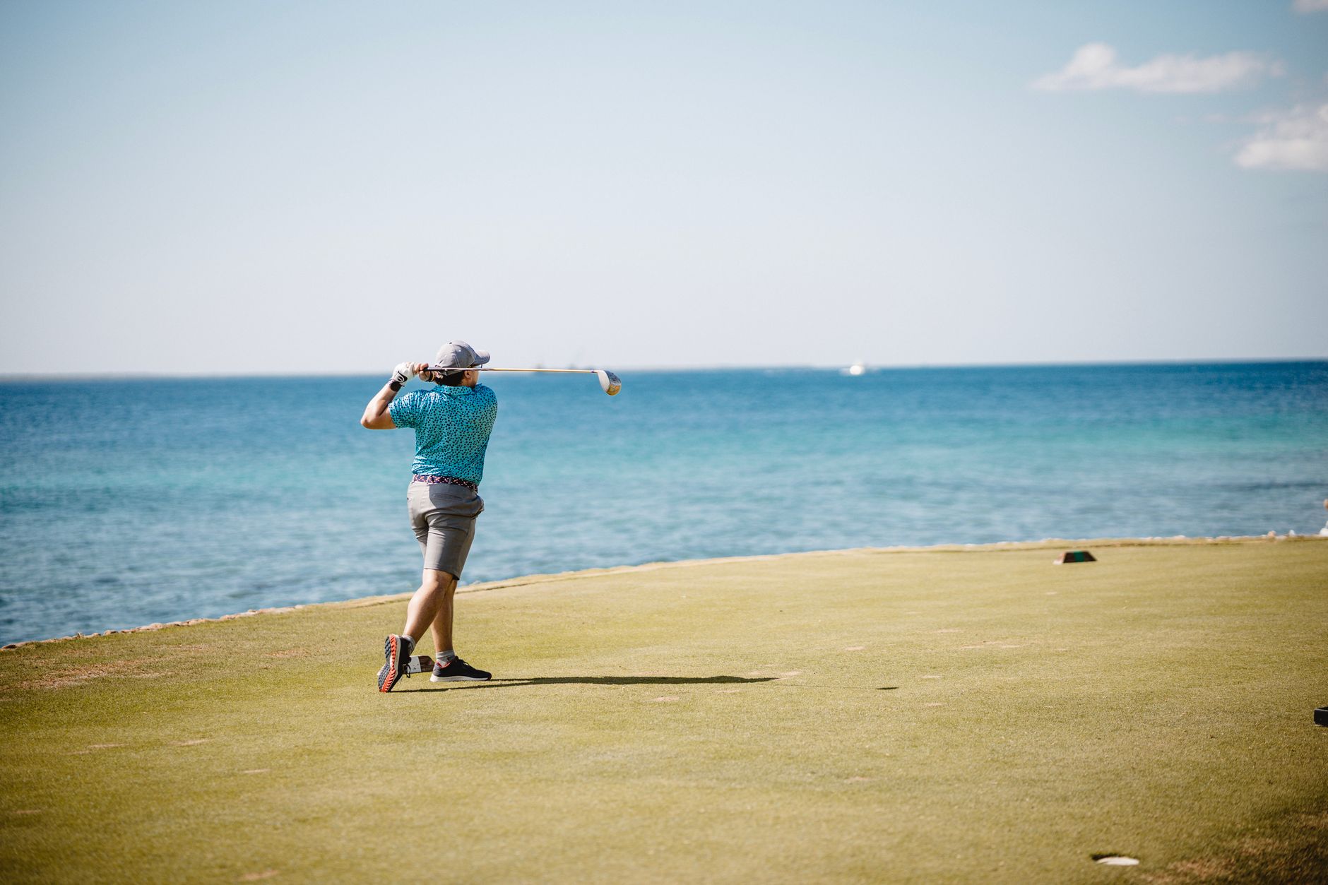 A man tees off at a seaside golf course, enjoying a sunny day and ocean view. — photograph by Sebastian Luna on Pexels