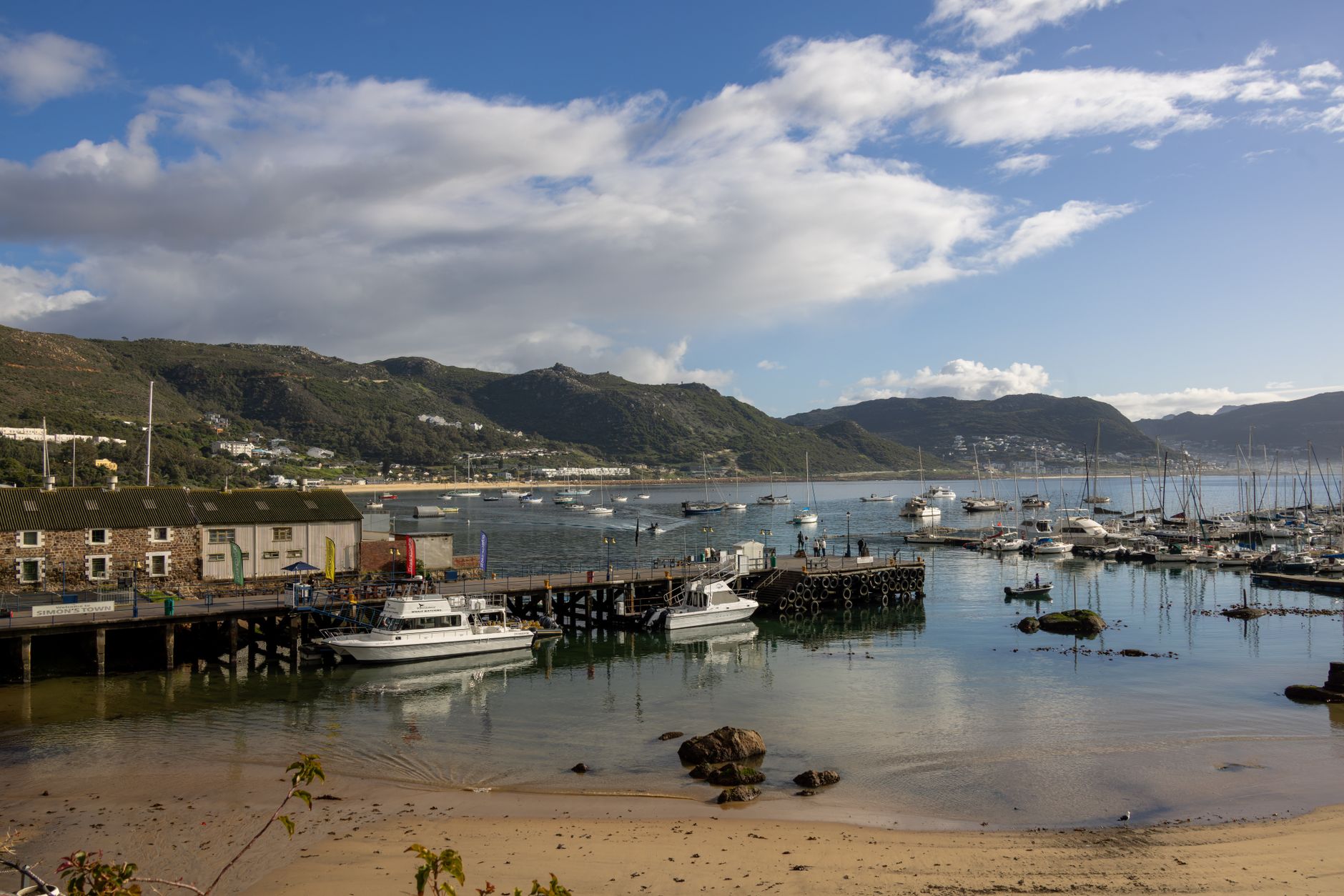 Beautiful Knysna Lagoon view featuring boats, docks, and lush hills under a blue sky. — photograph by Magda Ehlers on Pexels